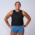 Smiling woman in GORUCK black tank top and blue shorts, studio fitness apparel photo