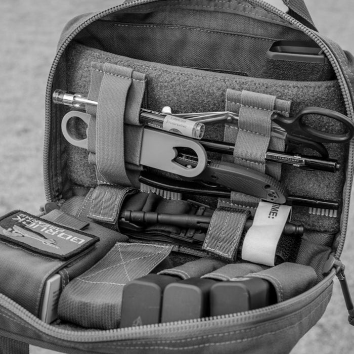 The Tourniquet Attachment opens to reveal scissors, a pen, trauma shears, and other tools organized with hook-and-loop straps and a dedicated tourniquet holder for fast access.