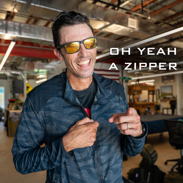 Smiling man in sunglasses points to his jacket zipper; text reads "OH YEAH A ZIPPER." The Warm Up Full Zip features ToughDry shoulders and is proudly made in the USA.