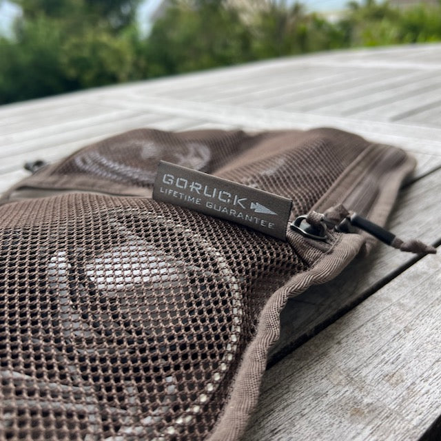 Close-up of the Wire Dopp - Waxed Canvas pouch with a "GORUCK Lifetime Guarantee" tag, ideal for organizing your EDC essentials, displayed outdoors on a wooden surface.
