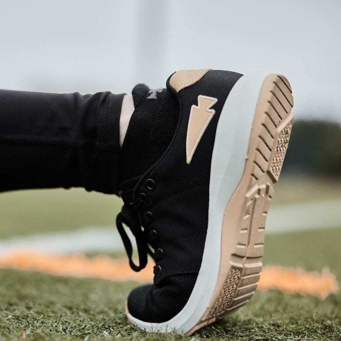 GORUCK black rucking shoe with tan sole, close-up on turf field, outdoor fitness gear