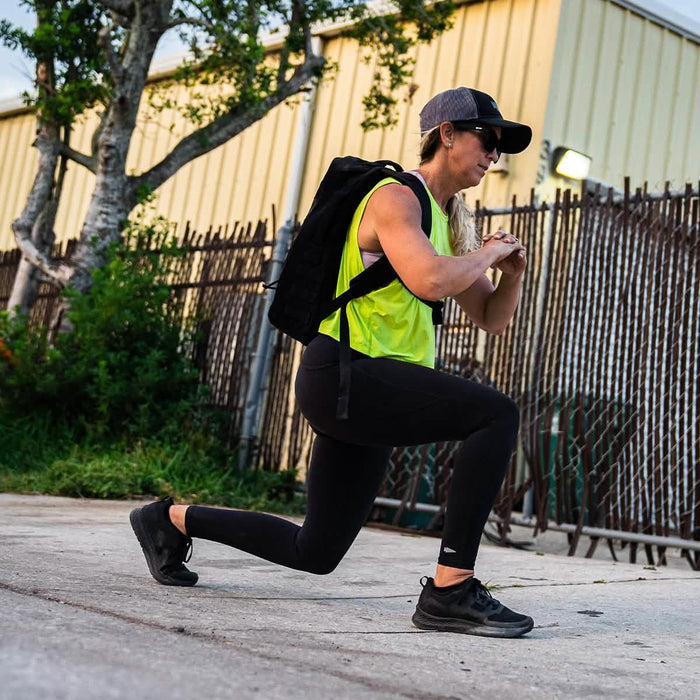 Woman wearing GORUCK backpack doing outdoor lunges in athletic gear