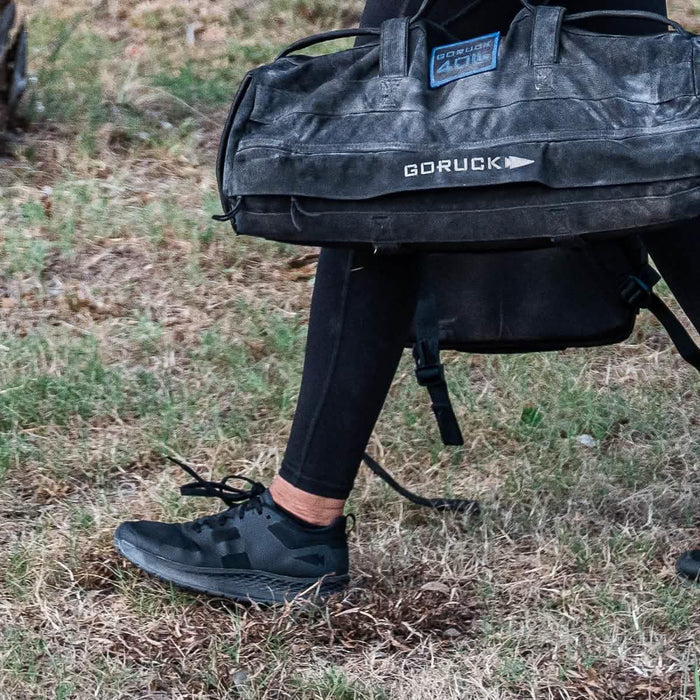 GORUCK sandbag and black rucking shoes on grass, outdoor fitness training gear